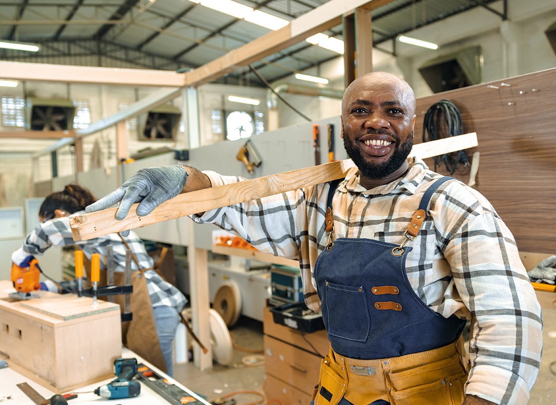 Insurance by Industry - Happy carpenter enjoying working in large wood workshop